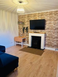 uma sala de estar com lareira e televisão de ecrã plano em Whiteley's Cottages em Dumbarton