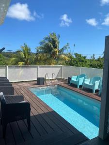 a swimming pool with blue chairs on a deck at Le domaine de Périolat in Le François