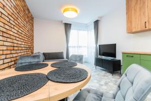 グダニスクにあるGrand Apartments - Doki Living & Foodhallのテーブル、椅子、テレビが備わる客室です。