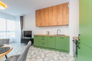 une cuisine avec des placards verts et un salon dans l'établissement Grand Apartments - Doki Living & Foodhall, à Gdańsk