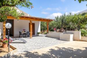 a patio with a table and chairs and trees at Case Vacanza Loria in Castelluzzo