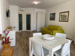 a living room with a white table and a green couch at Appartamento Dragunara in Alghero