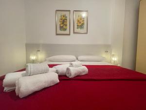 a bedroom with two beds with red sheets and white towels at Appartamento Dragunara in Alghero +19 photos