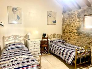 duas camas num quarto com uma parede de pedra em Domaine de Berducq em Monein