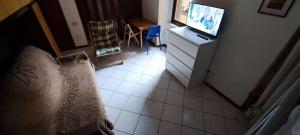 una camera da letto con TV e pavimento piastrellato di GRAYNITE-Old Village Apartment a Ponte di Legno