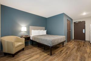 a bed and a chair in a room with blue walls at WoodSpring Suites Indio - Coachella Valley in Indio