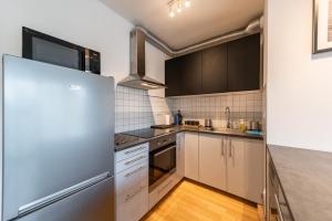 cocina con armarios blancos y nevera de acero inoxidable en Garden Towers Apartments en Praga