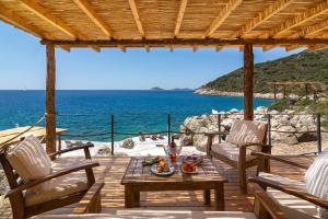 a wooden deck with chairs and a table and the ocean at Kalamar Beach 5 in Kaş