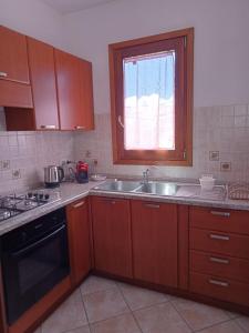 a kitchen with wooden cabinets and a sink and a window at Il Girasole casa vacanze in Porto San Paolo