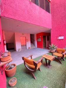 różowy budynek z krzesłami i stołem oraz patio w obiekcie Hotel Flamingos w mieście Guadalajara