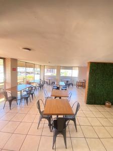 una caffetteria con tavoli, sedie e finestre di Hotel Flamingos a Guadalajara