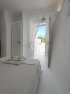 a white bedroom with a bed and an open door at Καμάρα (Kamara) cave rooms in Triovasálos +19 photos