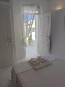 a white bedroom with a bed with two towels on it at Καμάρα (Kamara) cave rooms in Triovasálos