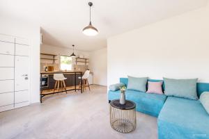 a living room with a blue couch and a kitchen at Yanka 4 Houses in Ljubaništa