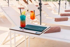a table with a laptop and two cocktails on it at The Londoner Hotel St. Julian's in St. Julianʼs