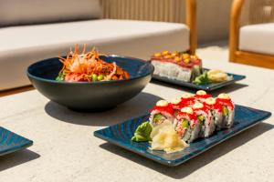 a table with three plates of sushi and a bowl of salad at The Londoner Hotel St. Julian's in St. Julianʼs