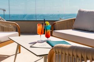 a table with two cocktails on a balcony at The Londoner Hotel St. Julian's in St. Julianʼs