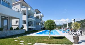a villa with a swimming pool in front of a building at Eleonas View Suites in Nea Peramos