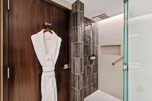 a white robe hanging in a bathroom with a shower at NH Collection Monterrey San Pedro in Monterrey