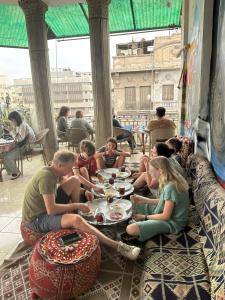 Un groupe de personnes assises autour d'une table avec de la nourriture dans l'établissement Cecilia Hostel, au Caire