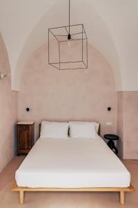 a bedroom with a large white bed and a chandelier at Casale Madre in Ostuni