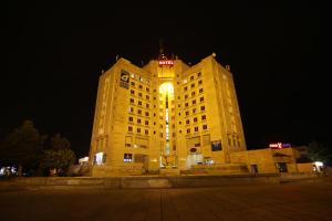 een groot geel gebouw met 's nachts een klokkentoren bij Hotel Rustavi in Rustavi