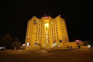 un gran edificio amarillo con una torre de reloj por la noche en Hotel Rustavi, en Rustavi