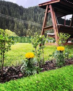 un giardino con fiori gialli e un gazebo di Guest House Recharge a Govedartsi
