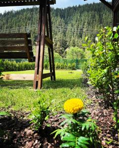eine Bank im Gras neben gelben Blumen in der Unterkunft Guest House Recharge in Govedartsi