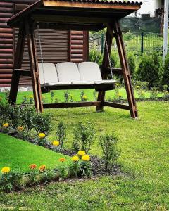 a swing in a yard with flowers at Guest House Recharge in Govedartsi