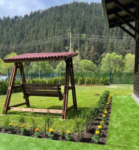 Guest House Recharge في جوفيدارتسي: أرجوحة خشبية في حديقة بها زهور