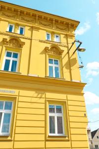 un bâtiment jaune avec quatre fenêtres au-dessus dans l'établissement Apartmány Plzeň Rolnické náměstí 8, à Plzeň