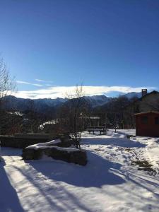 a snow covered yard with a view of the mountains at Maison de montagne proche des Angles in La Llagonne +10 photos
