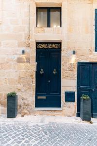 セントジュリアンズにあるSuite 4 at Palazzo Seraphim Boutique living in St Juliansの2つの黒いドアと2つの植物がある建物