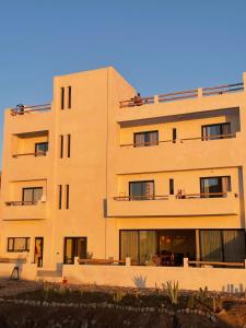 ein großes, braunes Gebäude mit Menschen auf den Balkonen in der Unterkunft L'Oued the lodge in Imsouane