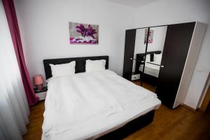 ein Schlafzimmer mit einem weißen Bett mit einem schwarzen Kopfteil in der Unterkunft My Place in Cluj-Napoca 7 Nights Minimum Stay in Cluj-Napoca