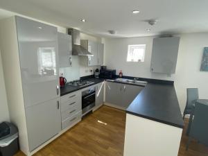 eine Küche mit weißen Schränken und einer schwarzen Arbeitsplatte in der Unterkunft Liberty Garden (Luxury 1bd Apt) in Portishead