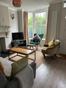 a living room with a couch and chairs and a table at Sea Song Cottage in Broadstairs