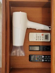a hair dryer and remote control in a wooden drawer at Sense of Haiya in Chiang Mai
