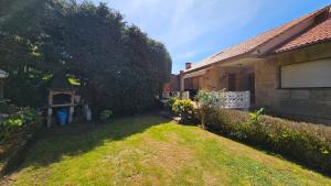 einen Hinterhof eines Hauses mit einem Garten mit einem Zaun in der Unterkunft CASA MEXILLOEIRA in O Grove