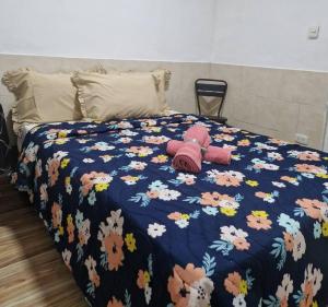 a teddy bear sitting on a bed with a flower blanket at La Alborada Casa boutique in Villavicencio +2 photos