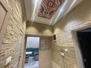 een hal die leidt naar een woonkamer met een stenen muur bij Cozy apartment 3 in Samarkand +13 foto's