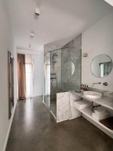 een badkamer met een douche, een wastafel en een spiegel bij Chipibeach, Hostal Boutique in Chipiona