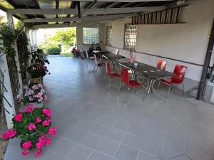a patio with tables and red chairs and flowers at Rooms Laguna Maresol in Jagodje