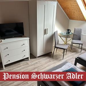 una sala de estar con TV y una cómoda con una bañera de hidromasaje en Pension Schwarzer Adler, 