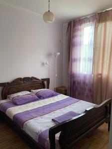 a bedroom with a bed with purple sheets and a window at Guesthouse Mirabela in Shekvetili