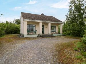 una piccola casa bianca con un vialetto di ghiaia di Hideaway a Ballinrobe