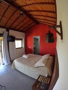 a bedroom with a bed and a red wall at Chalés Vila Real - Tranquilidade na Serra de Carrancas - Piscina com uma vista espetacular do Pôr do Sol in Carrancas
