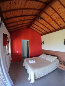 a bedroom with a bed with a red wall at Chalés Vila Real - Tranquilidade na Serra de Carrancas - Piscina com uma vista espetacular do Pôr do Sol in Carrancas