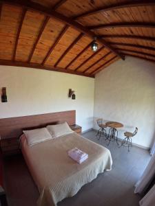 a bedroom with a bed and a table with chairs at Chalés Vila Real - Tranquilidade na Serra de Carrancas - Piscina com uma vista espetacular do Pôr do Sol in Carrancas